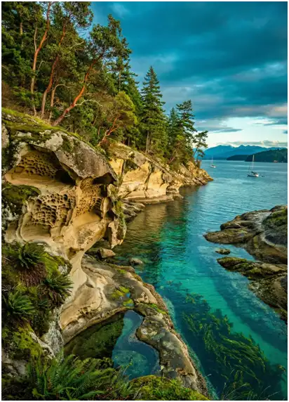 Eroded sandstone shoreline with turquoise water and anchored sailboats