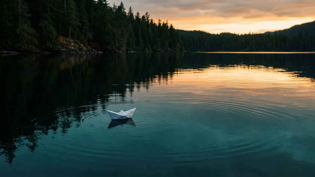 A small paper boat floats on still dark water at dusk, gentle ripples spreading from it.
